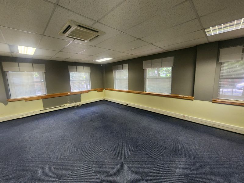 An empty office space featuring suspended ceilings, recessed lighting, ducted air conditioning, and perimeter trunking for electrical and data connectivity.