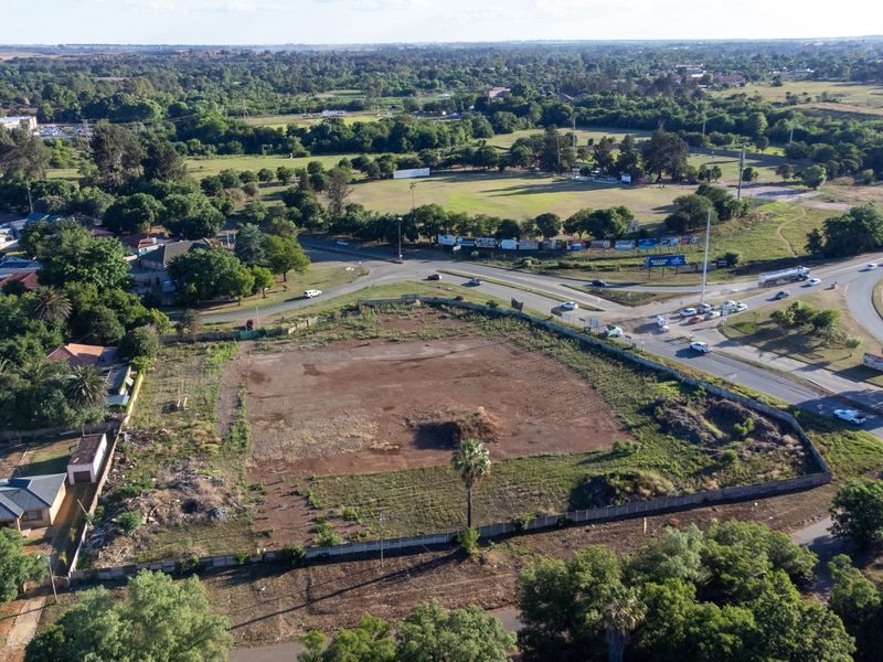 Aerial view of a vacant, undeveloped retail-zoned plot situated at a prominent road intersection, offering significant potential for commercial development.