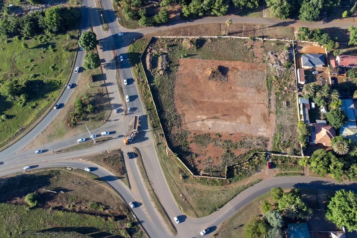 Aerial view of a vacant corner plot situated at a road intersection, offering significant potential for commercial development.