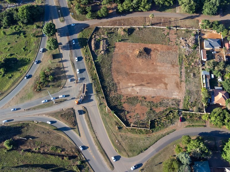 Aerial view of a vacant corner plot situated at a road intersection, offering significant potential for commercial development.