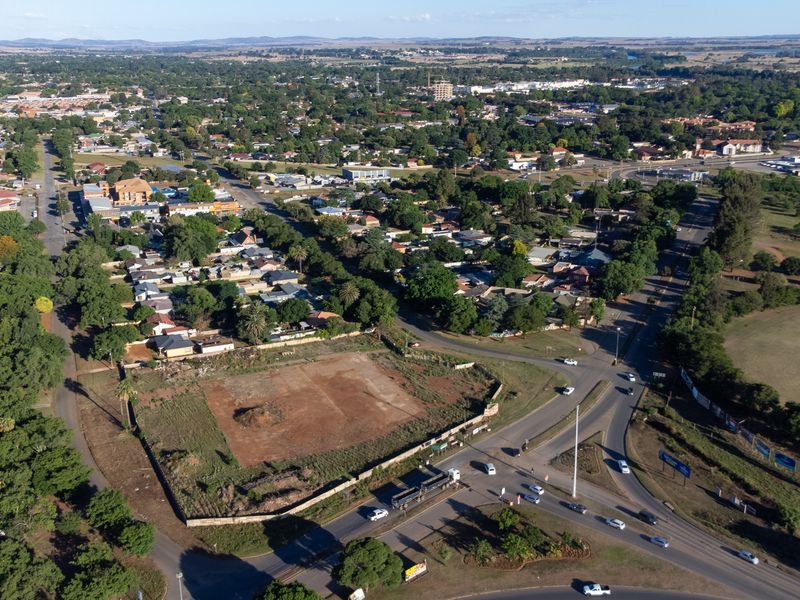 Aerial view of a vacant commercial development site situated at a prominent street intersection within a suburban retail and residential area.