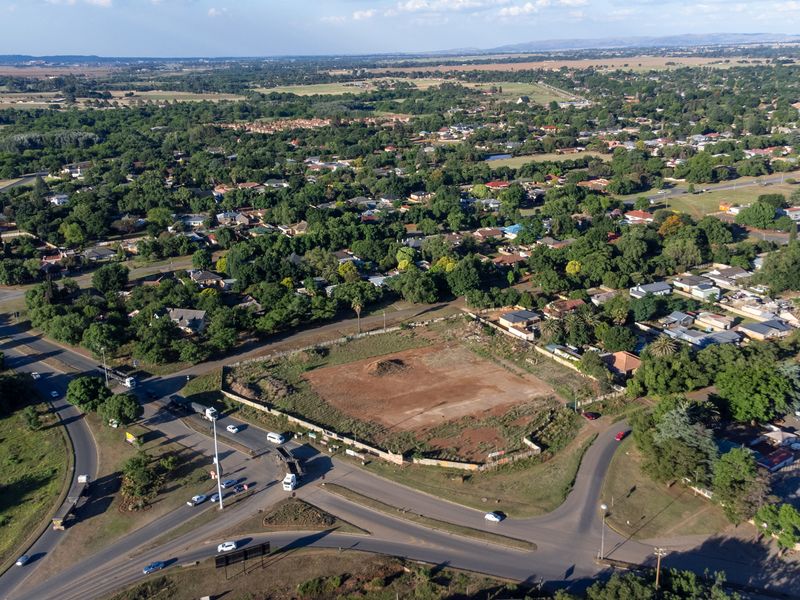 Aerial view of a vacant commercial development site situated at a prominent road intersection, surrounded by established residential and commercial infrastructure.