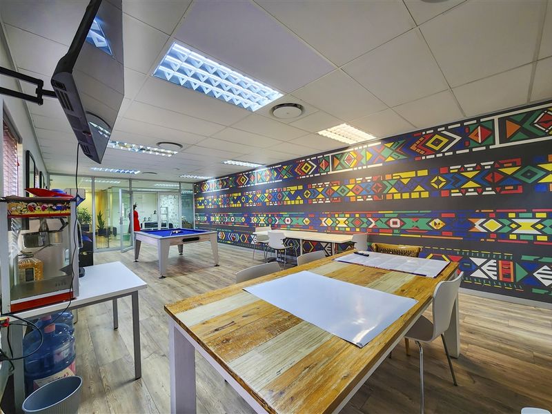 A modern office space featuring a vibrant patterned feature wall, suspended ceiling with recessed lighting, and durable laminate flooring.