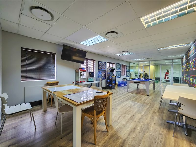 Spacious open-plan office area featuring laminate flooring, suspended ceilings with recessed lighting, and glass partitioning for a modern, collaborative workspace environment.