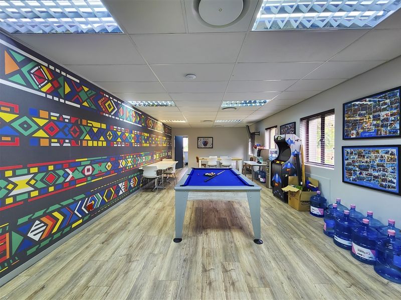 A spacious office breakout area featuring laminate flooring, suspended ceilings with recessed lighting, and a decorative patterned feature wall.