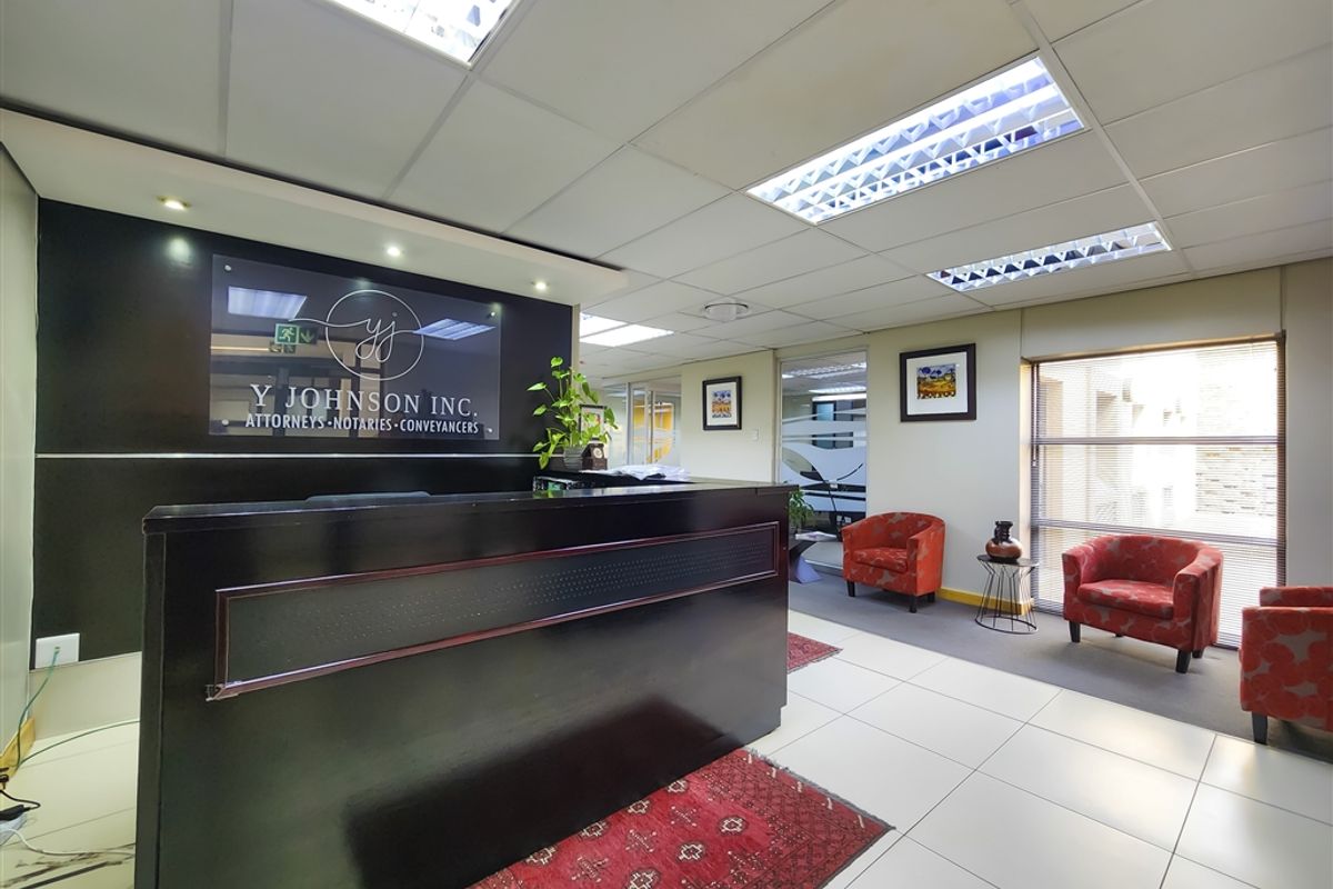 Professional office reception area featuring a built-in reception desk, suspended ceiling with integrated lighting, and tiled flooring.