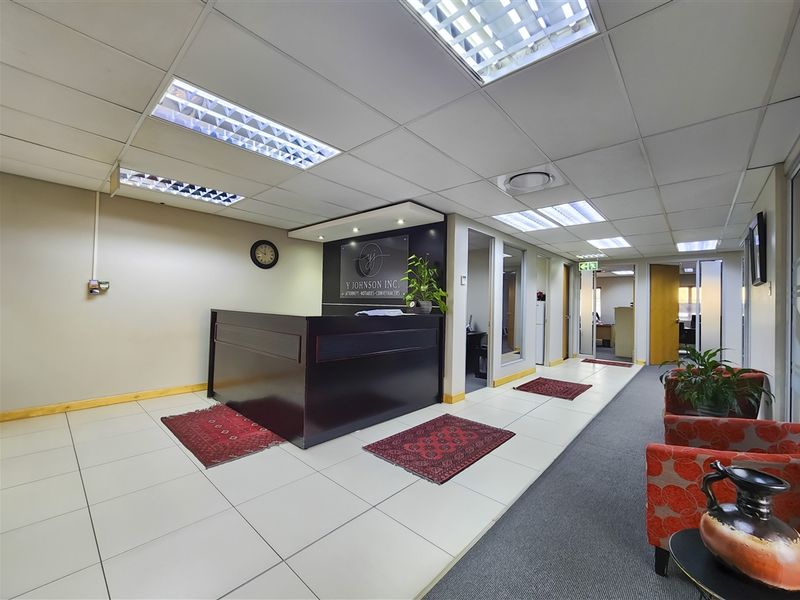 Professional office reception area featuring a built-in reception desk, suspended ceiling with integrated lighting, and a combination of tiled and carpeted flooring.