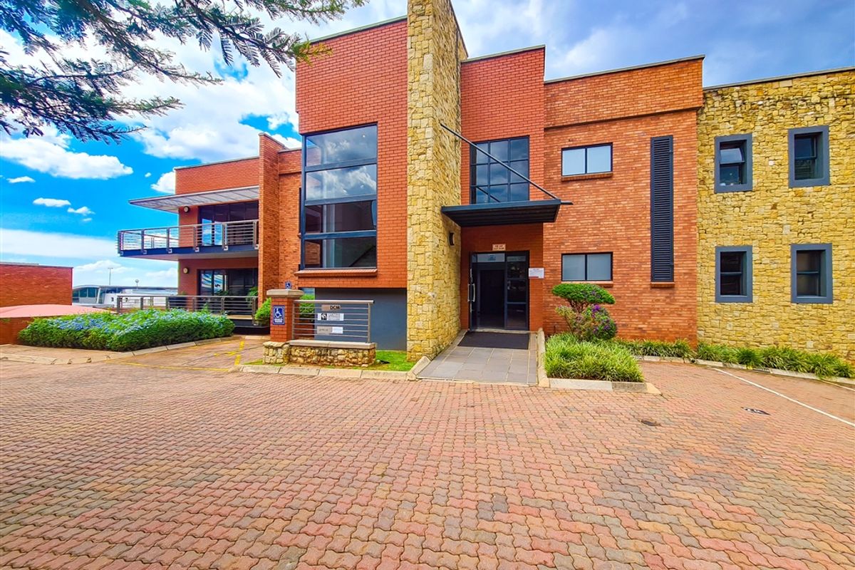 A professional office building exterior featuring a combination of red brick and stone cladding, with a paved driveway and accessible entrance ramp.