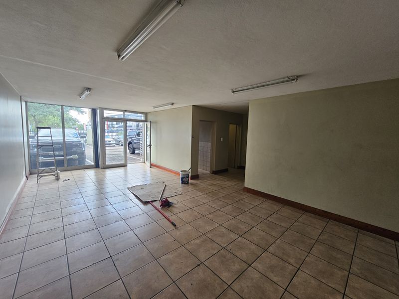 Open plan industrial office or retail space featuring tiled flooring, large glass frontage, and direct street access.