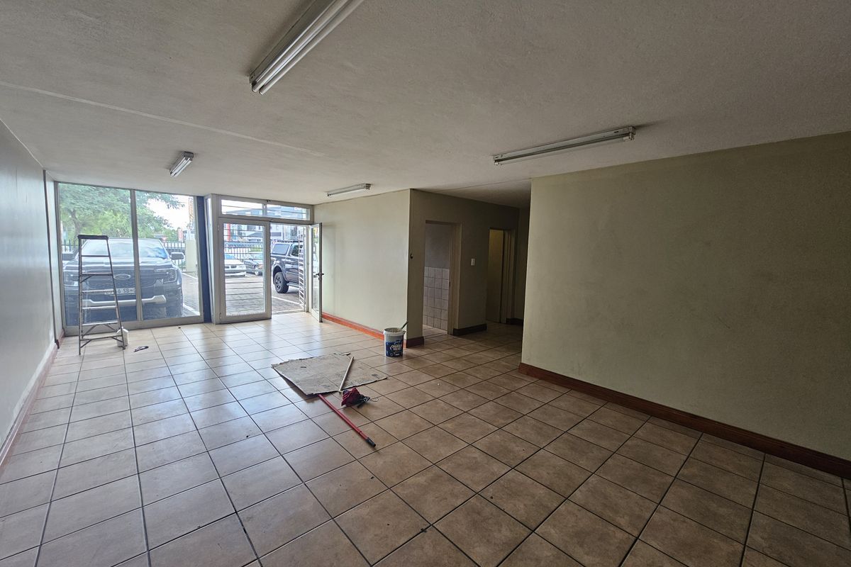 Open plan industrial office or retail space featuring tiled flooring, large glass frontage, and direct street access.