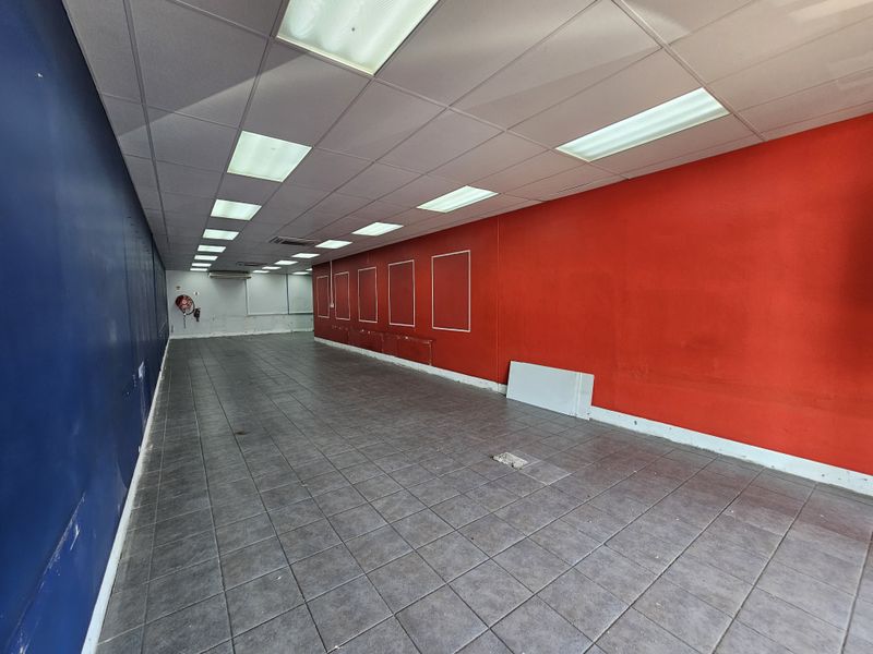 An empty retail space featuring tiled flooring, recessed ceiling lighting, and high-contrast blue and red painted walls, suitable for various commercial business applications.