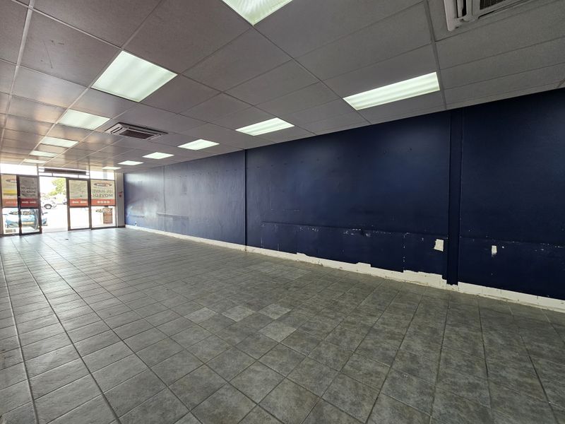 Open-plan retail space featuring tiled flooring, recessed ceiling lighting, and a large display window, currently vacant and ready for custom fit-out.