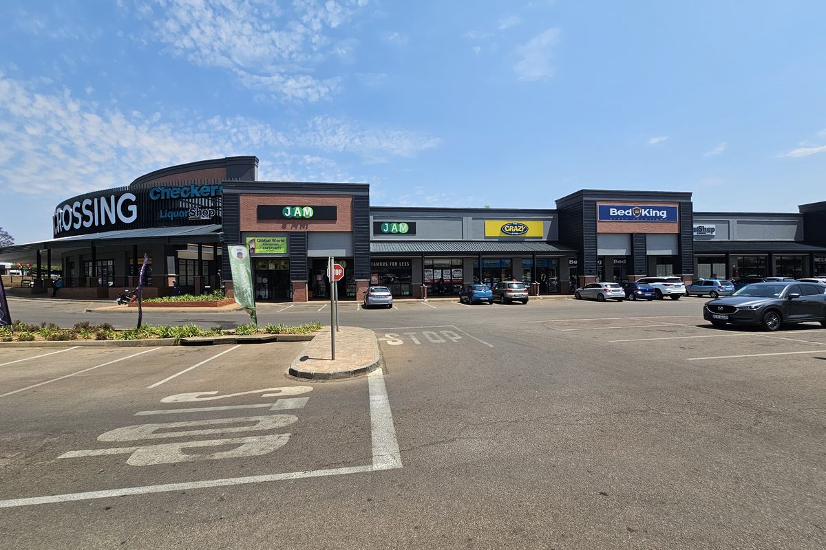 A wide-angle view of a modern retail shopping center exterior featuring multiple storefronts, paved parking area, and clear signage.