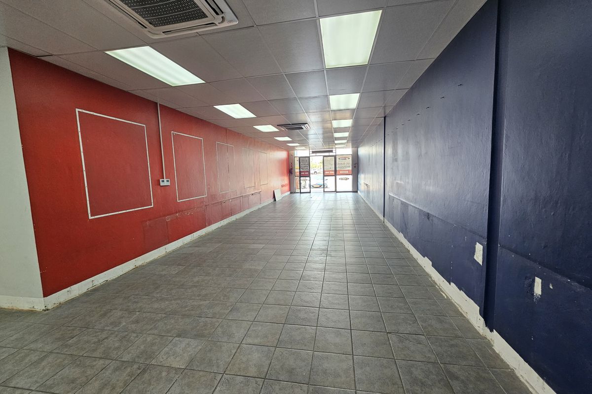 An empty retail space featuring tiled flooring, recessed ceiling lighting, and a central air conditioning unit, ready for custom fit-out.