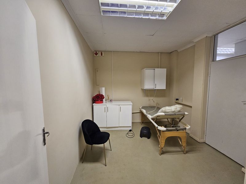 A functional treatment room featuring a drop ceiling with recessed lighting, neutral wall finishes, and built-in cabinetry suitable for professional or clinical use.