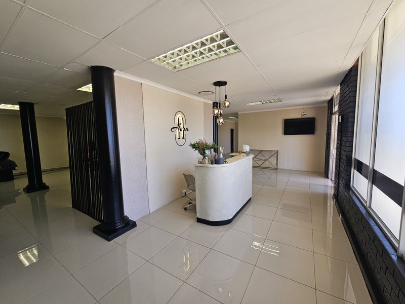 A professional retail reception area featuring a curved service desk, tiled flooring, recessed ceiling lighting, and decorative structural columns.