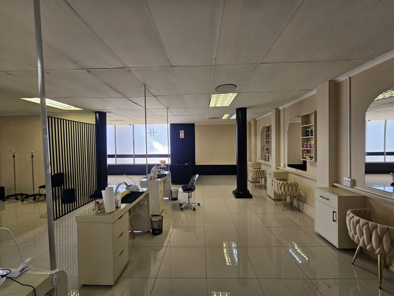 Spacious retail salon area featuring tiled flooring, recessed lighting, built-in cabinetry, and decorative wall mirrors, suitable for beauty or professional services.