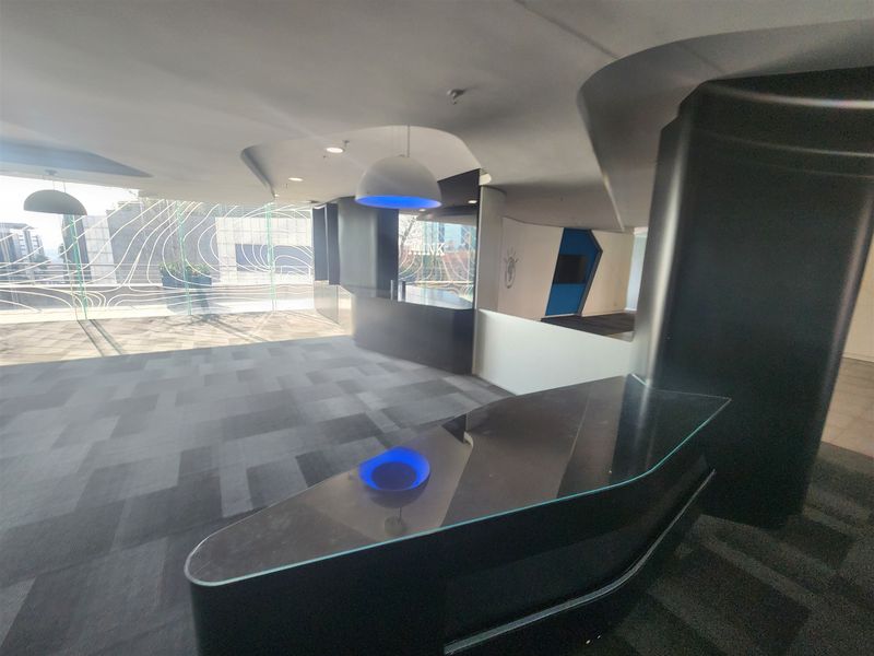 Modern office reception area featuring a sleek built-in desk, contemporary ceiling design, and large glass windows providing ample natural light.