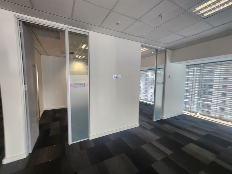 Modern office space featuring glass partition walls, sliding doors, suspended ceilings, and carpet tiles, offering a clean and professional work environment.