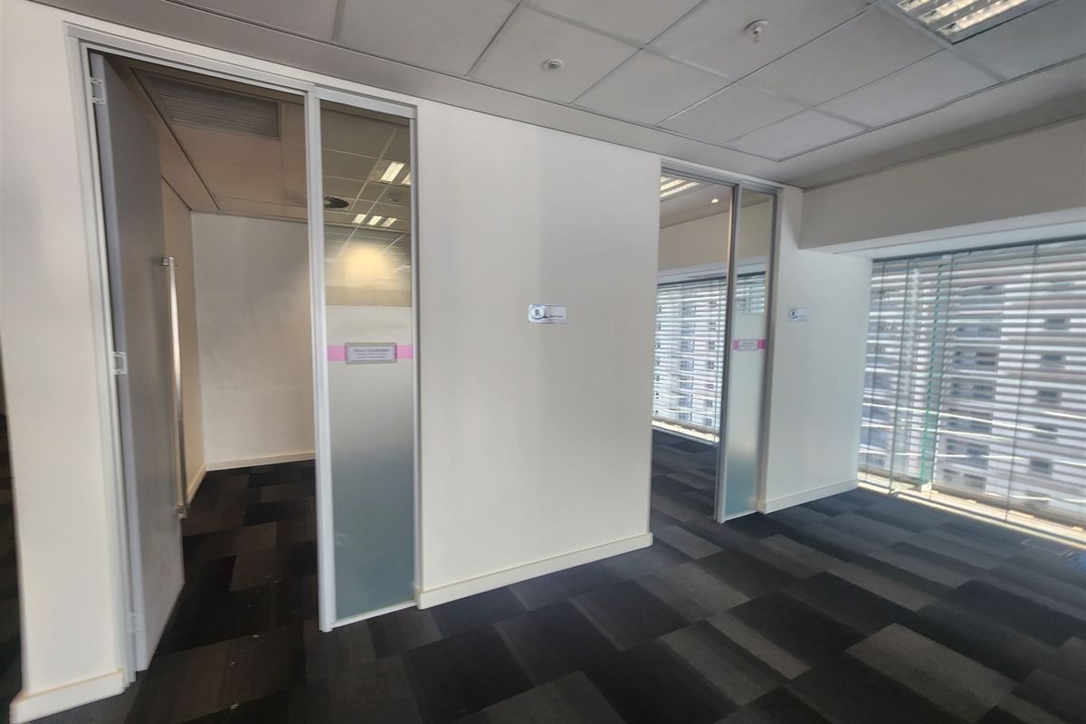 Modern office space featuring glass partition walls, sliding doors, suspended ceilings, and carpet tiles, offering a clean and professional work environment.