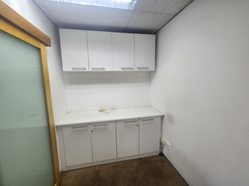 A small office space featuring built-in white cabinetry, a drop ceiling, and a sliding glass door, currently vacant and ready for use.