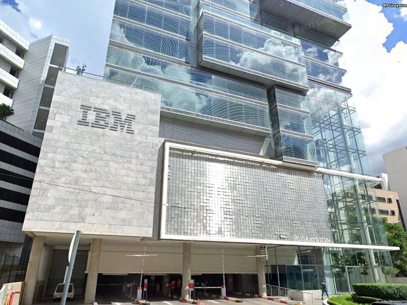 Modern commercial office building facade featuring glass curtain walls, stone cladding, and a secure underground parking entrance.
