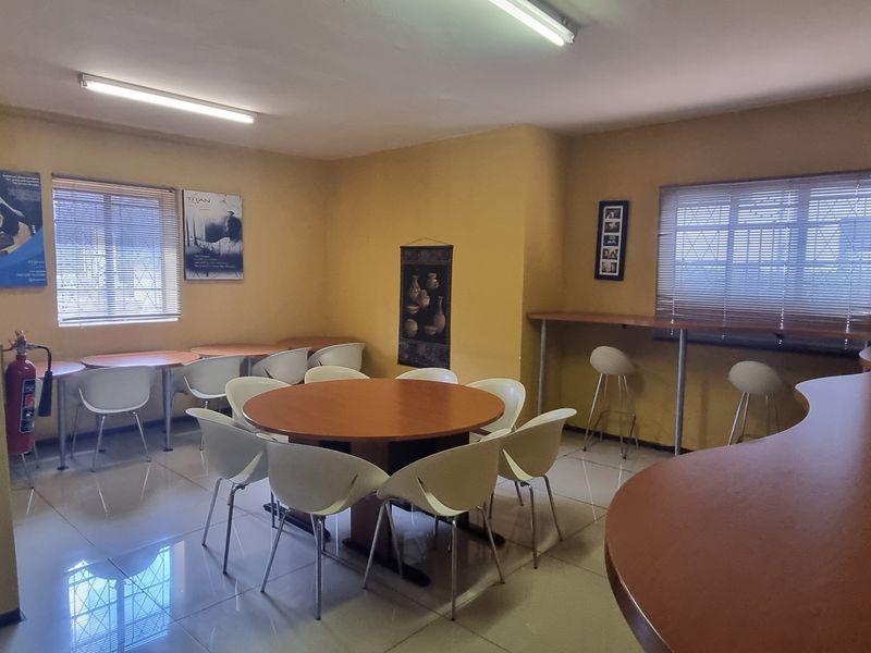 A functional office or break room space featuring tiled flooring, built-in counter space, and security bars on the windows.