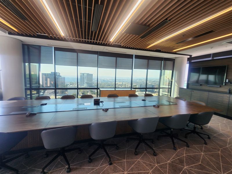 Modern professional boardroom featuring a slatted timber ceiling, floor-to-ceiling windows with city views, and integrated cabinetry.