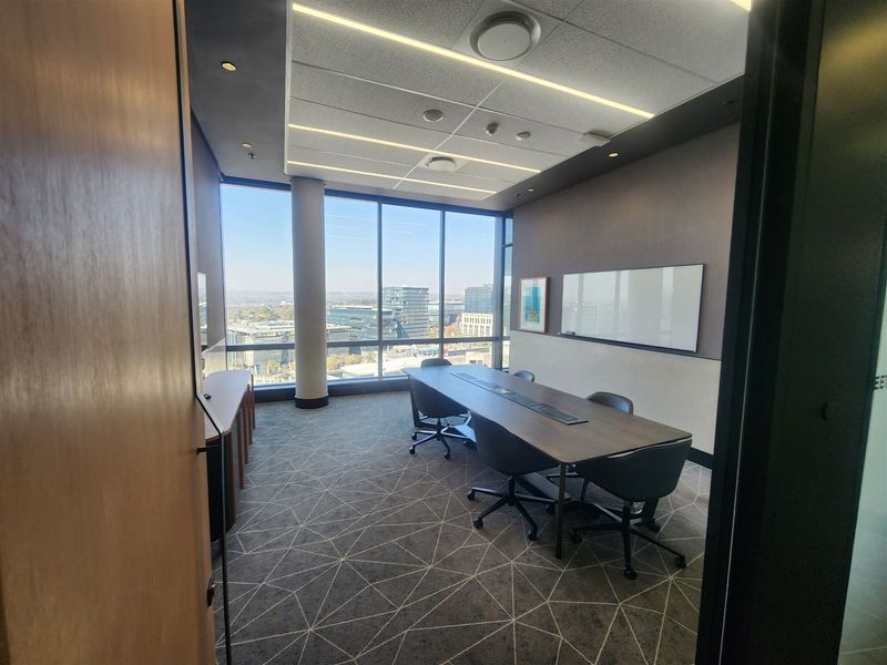 Modern professional office meeting room featuring floor-to-ceiling windows with city views, integrated ceiling lighting, and a wall-mounted whiteboard.