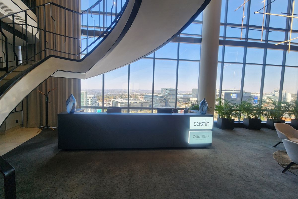 Modern office reception area featuring a striking curved staircase, floor-to-ceiling glass facade with panoramic city views, and a professional built-in reception desk.