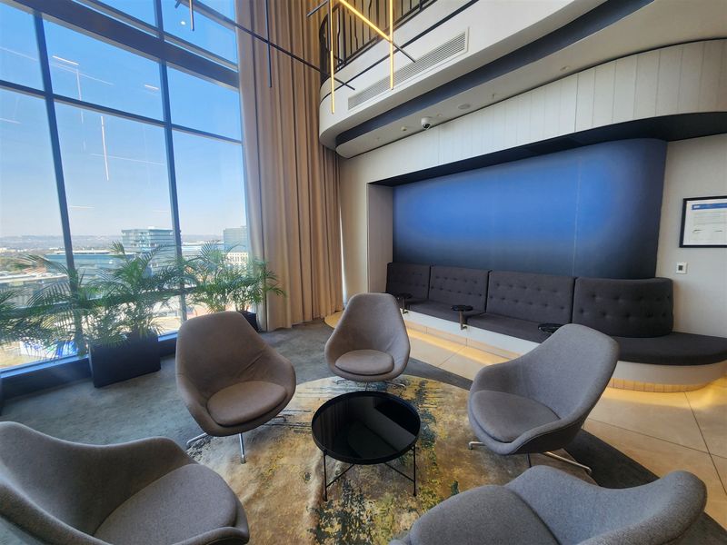 Modern office lounge area featuring floor-to-ceiling windows with expansive views, built-in bench seating, and high-quality contemporary finishes.