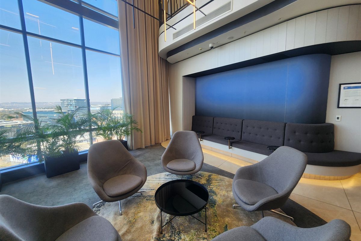 Modern office lounge area featuring floor-to-ceiling windows with expansive views, built-in bench seating, and high-quality contemporary finishes.