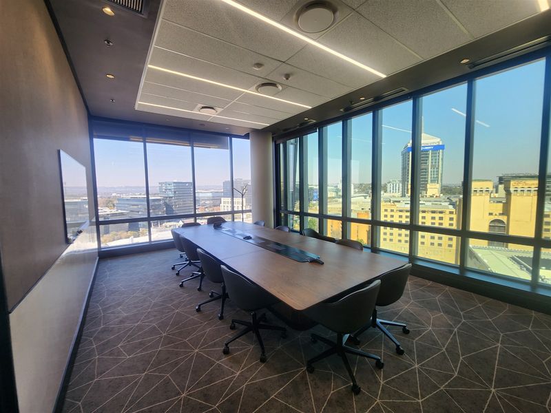 Modern professional boardroom featuring floor-to-ceiling windows with expansive city views, recessed linear lighting, and high-quality commercial finishes.