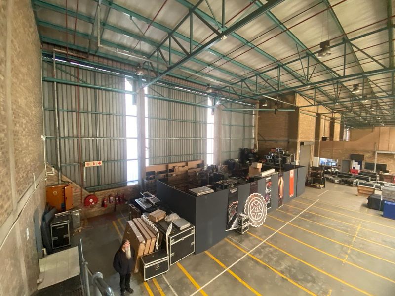 Spacious industrial warehouse featuring high-clearance steel roof trusses, corrugated metal walls, and durable concrete flooring with marked loading zones.