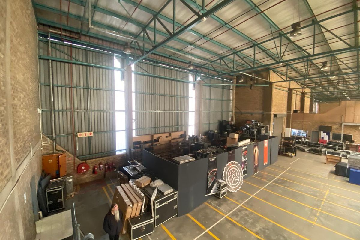 Spacious industrial warehouse featuring high-clearance steel roof trusses, corrugated metal walls, and durable concrete flooring with marked loading zones.