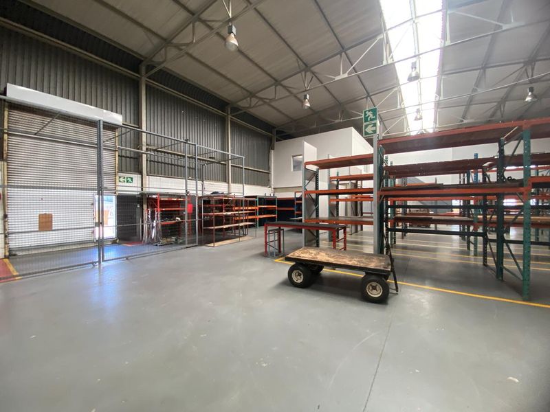 Spacious industrial warehouse unit featuring high ceilings with skylights, durable epoxy flooring, secure metal partitioning, and roller shutter access.