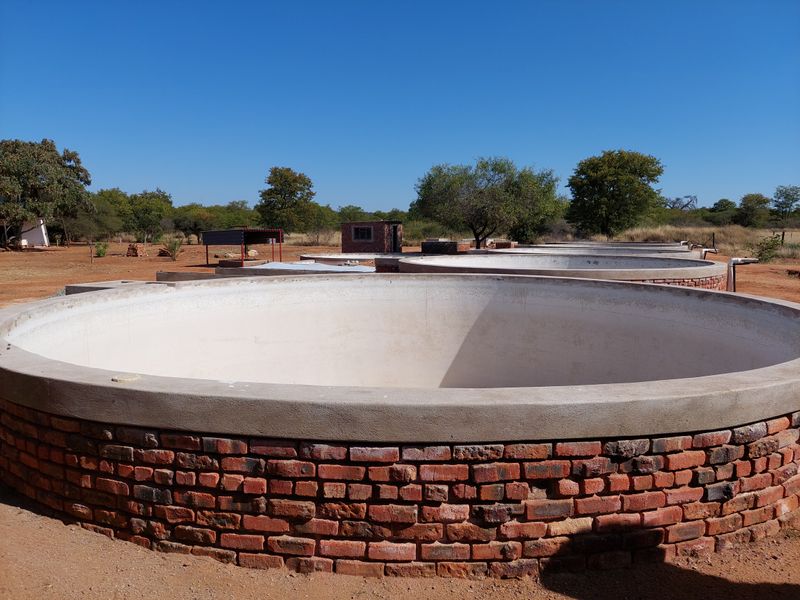 A series of circular brick-built water reservoirs or storage tanks situated in an open farm landscape.
