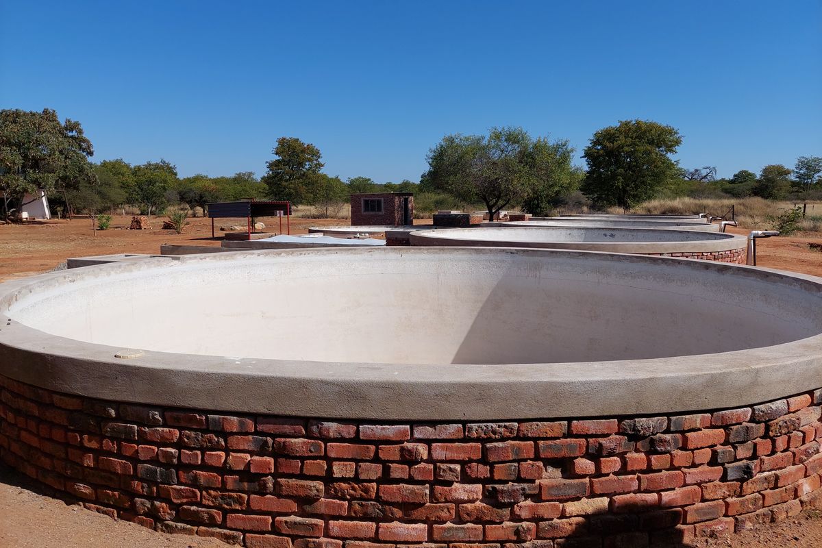 A series of circular brick-built water reservoirs or storage tanks situated in an open farm landscape.