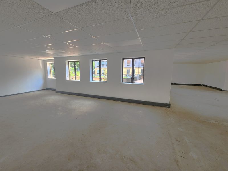 A spacious, vacant open-plan office area featuring a suspended ceiling, large windows, and unfinished flooring, ready for custom fit-out.