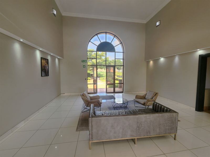 Spacious office entrance lobby featuring high ceilings, large arched glass doors, and polished tile flooring with modern recessed lighting.