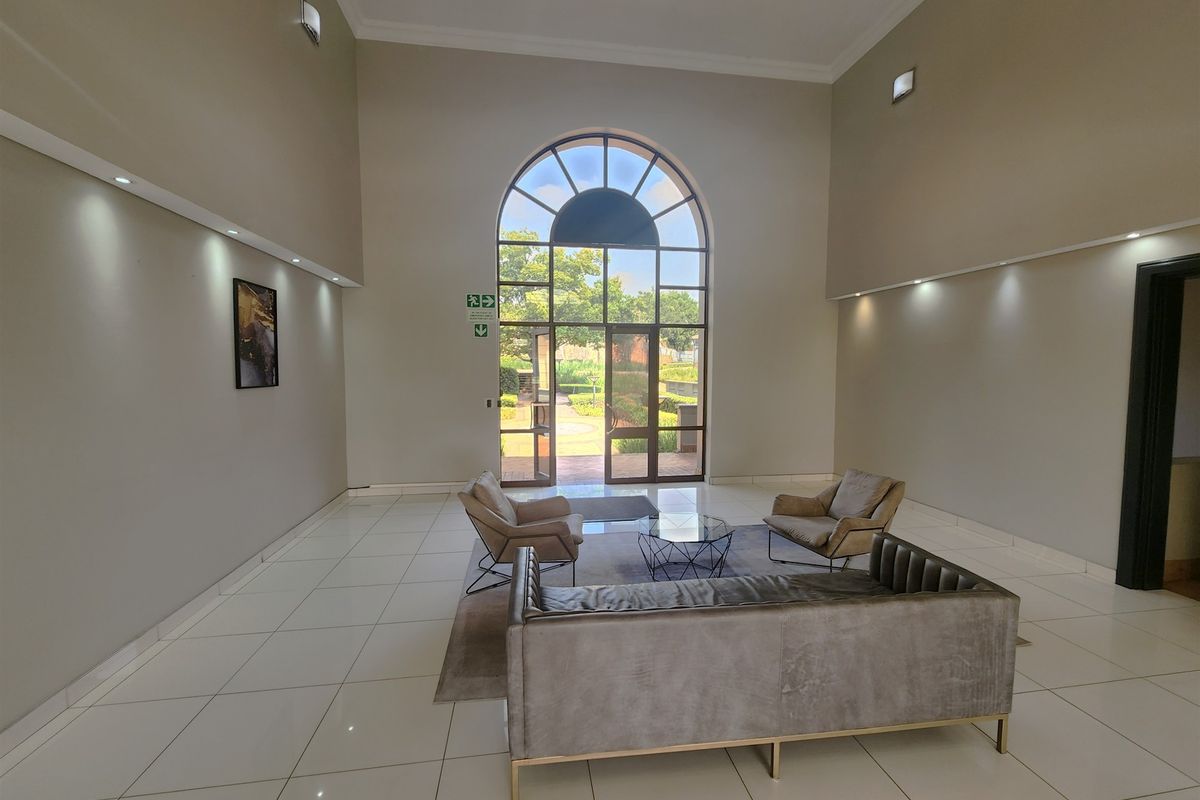 Spacious office entrance lobby featuring high ceilings, large arched glass doors, and polished tile flooring with modern recessed lighting.