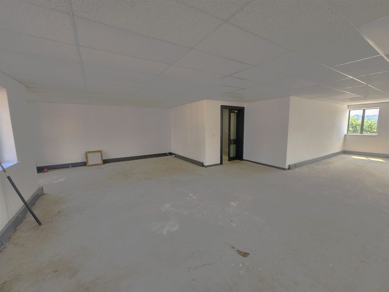 An empty, open-plan office space featuring a suspended ceiling, glass-paneled door, and concrete flooring, ready for custom fit-out.