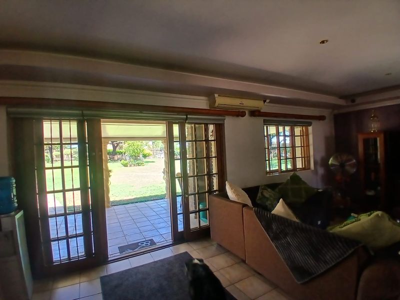 Spacious living room featuring tiled floors, air conditioning, and large sliding doors providing direct access to the outdoor patio and garden area.