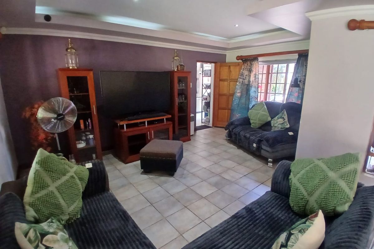 A living room featuring tiled flooring, recessed ceiling lighting, and crown molding, providing a functional space with direct access to adjacent areas.