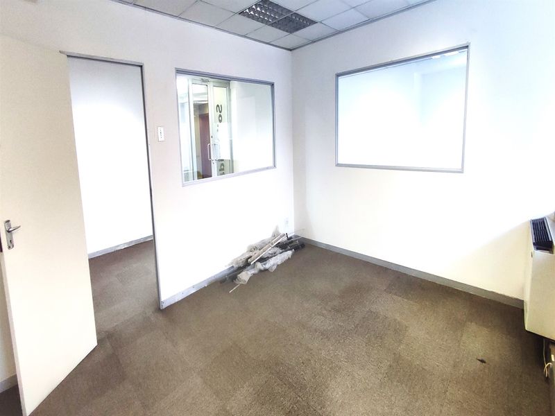 A vacant office space featuring carpeted flooring, suspended ceilings with recessed lighting, and internal glass partitions providing natural light flow.