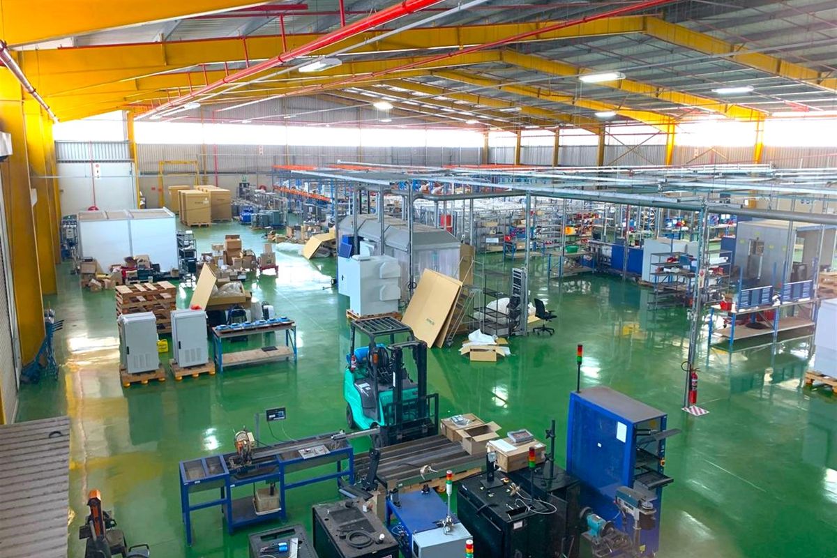 Spacious industrial warehouse facility featuring high ceilings with exposed steel trusses, fire sprinkler systems, and durable epoxy-coated flooring suitable for manufacturing or storage operations.
