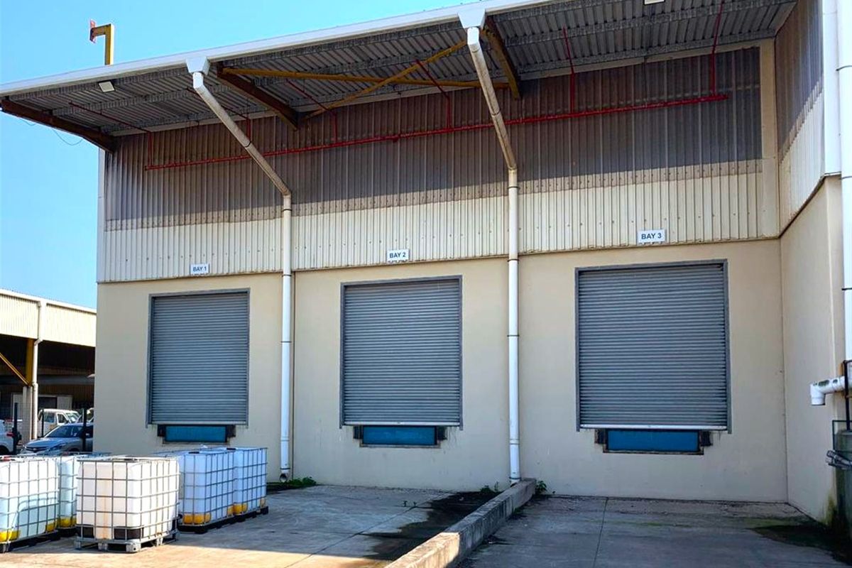 Industrial loading area featuring three roller shutter doors, concrete loading bays, and metal cladding exterior finish.
