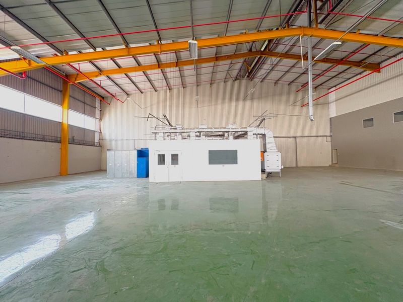 Spacious industrial warehouse featuring a high-clearance steel portal frame, epoxy-coated concrete flooring, fire sprinkler system, and a dedicated built-in spray booth.