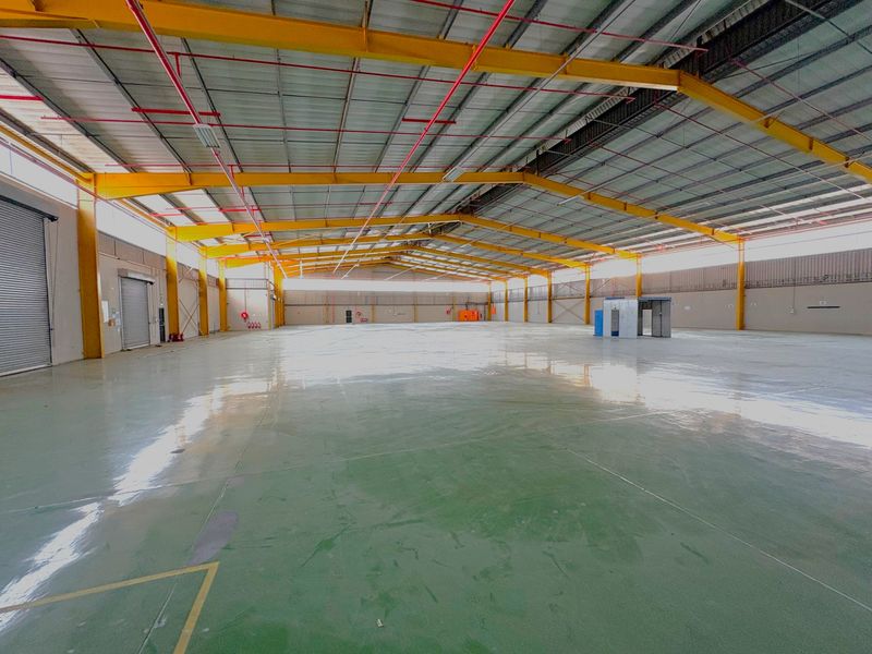 Spacious industrial warehouse featuring a high-clearance steel portal frame, polished epoxy flooring, and integrated fire sprinkler system, suitable for logistics or manufacturing operations.