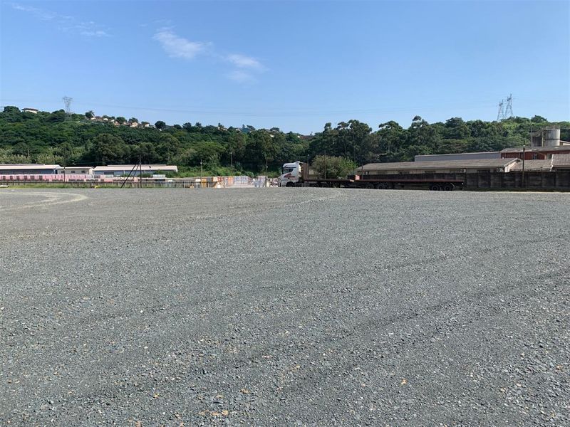 A wide-angle view of a large, level commercial vacant land plot featuring a gravel surface, suitable for industrial or logistics use.